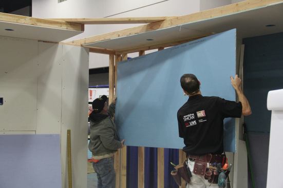 Put a generous bead of adhesive on every stud. When lifting the sheet, focus on getting one upper corner into place, keeping the sheet away from the wall so you don’t smear the adhesive across the back of the panel.