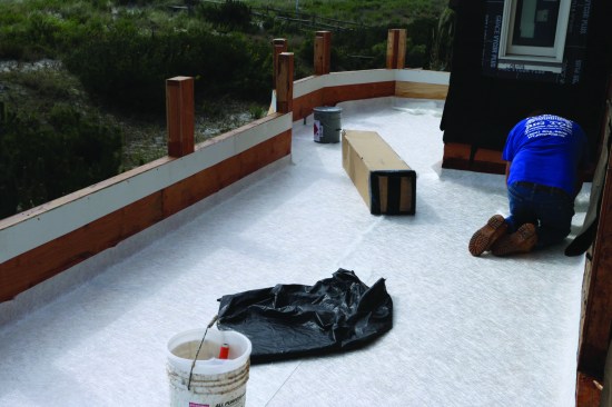 After the resin was allowed to cure for a day and then sanded smooth and thoroughly vacuumed, a layer of 1.5-ounce chopped fiberglass mat was spread out over the deck surface. Note how the mat extends up the parapet walls, to create a pan.