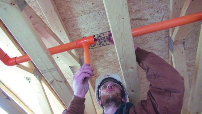 To make a CPVC pipe joint, both of the pieces to be attached need to be smeared with the solvent adhesive. Above, the installer applies a medium-thick coat of adhesive to the inside of the fittings.