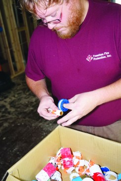 An installer wraps a sprinkler head’s threads with thread tape.