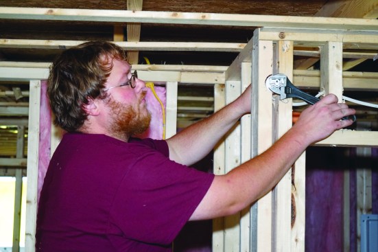 He levels the head in its fitting with a wrench.