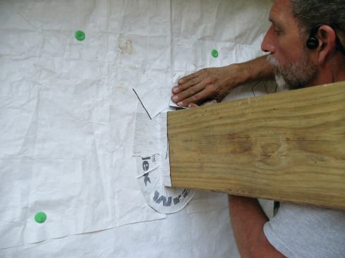 Finally, I fold the flap of housewrap back down over the flashing tape, and seal the cuts with scraps of flashing tape.