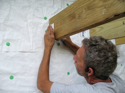 The tape should reach more than halfway up the sides of the joists, so that later it can be overlapped by the top piece of flashing tape.