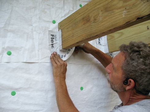 I use both hands to stretch the flashing tape evenly and form an arc around the bottom of the joist without too many wrinkles.