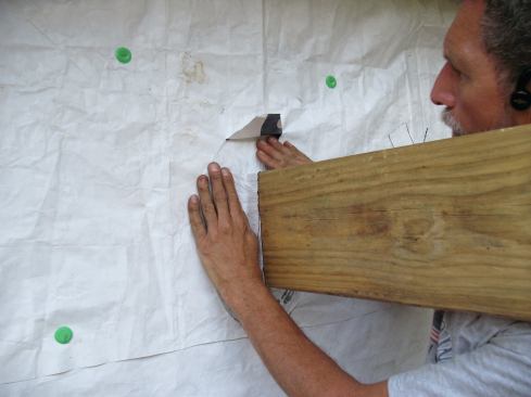 I flare the tape onto the wall and over the sheathing where the head flap is lifted.