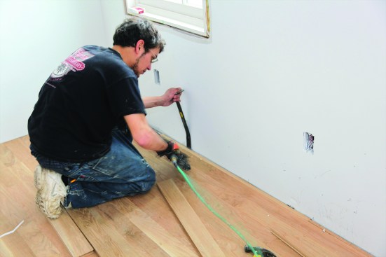 After cutting the last board, slip it into place and draw it tightly against the next-to-last board using a flat bar. Align the flat bar with a stud to keep it from damaging the drywall.