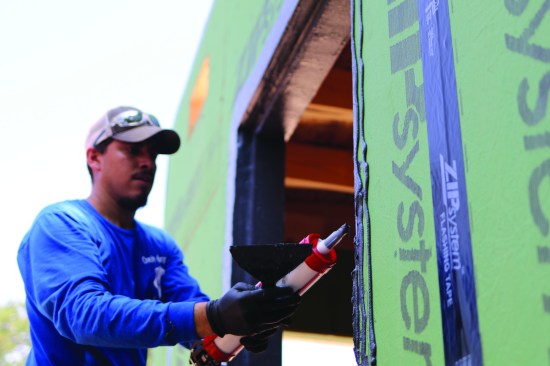 On a second recessed window, a carpenter demonstrates the use of Zip System Liquid Flash. For this product, Huber went with a trowel-grade, single-component material that has a viscosity somewhere between a joint filler and a brush formulation. Step one is to apply a thick bead of Liquid Flash in all the corners and seams, then apply multiple beads on the flat surfaces of the jambs and the step created for the recessed opening, and on the face of the sheathing.