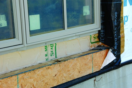 The opening had been flashed with a peel-and-stick material, the window unit installed, and then the housewrap simply folded over the returns