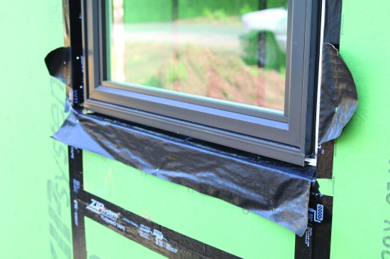 Unsure of what to do on a Zip System wall, a builder simply installed wide pieces of a paper-and-plastic-laminated flashing tape, which he planned to secure with Zip System sheathing tape. This detail would likely have deteriorated quickly and become a homeowner’s nightmare. With almost no roof overhang on this house, these openings will be exposed to a deluge of water.