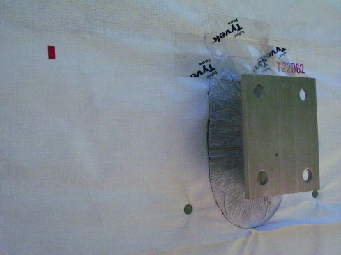 To seal the bracket to the housewrap and prevent leaks, the author applies another layer of tape over the top of the flexible flashing tape.