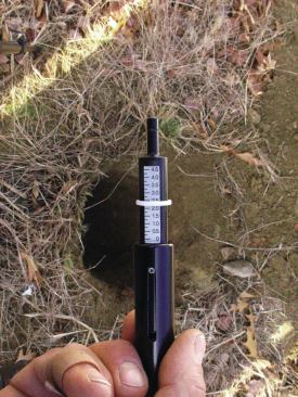 A penetrometer has a spring-loaded piston that retracts into the tool when it’s pushed down; when released, the tool relaxes to full extension leaving a friction indicator ring at the maximum level of compression. Here, the scale reads 2.25 tons, indicating a soil bearing capacity of 2.25 tons—or 4,500 pounds—per square foot. Because it’s difficult to take measurements at the bottom of footings deeper than arm’s length, the author tapes the penetrometer body to a stick and uses a mirror mounted to another stick to view the penetration scribe mark.