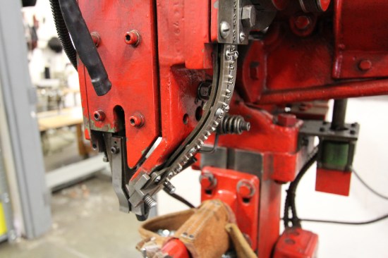 Those hollow pins are rivets. They're placed in a hopper at the top of the machine, fed down a slot on the side, and mechanically driven when they reach the bottom.