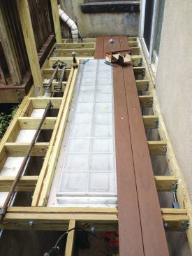 With the skylight secured to the framing, workers installed the TimberTech XLM decking, which was secured to the joists with hidden fasteners. The decking was laid out from the edge of the skylight rather than from one of the deck edges.