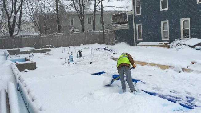 A worker shovels snow from the insulated subgrade at a Great Falls infill project in Portland, Maine, after a sudden March snowfall.