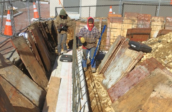 Crew members tying rebar and setting forms.

