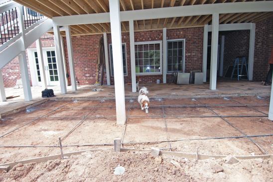 Extending an existing concrete patio is a straightforward project. The footings for the columns for the deck above were poured before the patio was put in; this way the load is transferred below the patio. Note that the tops of the footings are lower than the bottom of the new slab.