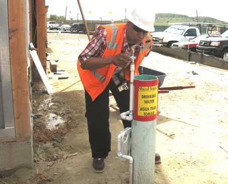 Every contractor or subcontractor with employees on a site is required to supply water for its own employees. That’s not the developer’s responsibility. But developers or general contractors are free to supplement the employer-supplied water if they choose to do so. Here, the author takes a drink from a water fountain set up by Shea Homes, the developer and prime contractor on this site. Shea routinely makes water fountains available to all the workers on sites they control.