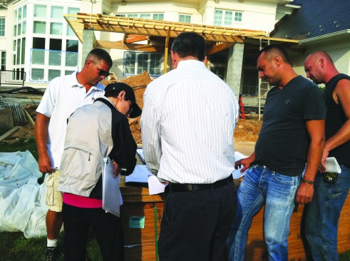 Frequent ad-hoc meetings between project managers, production managers, and trade contractors to iron out critical details help to keep jobs moving and on schedule. Here, metal roof details are being discussed with the roofing contractor.