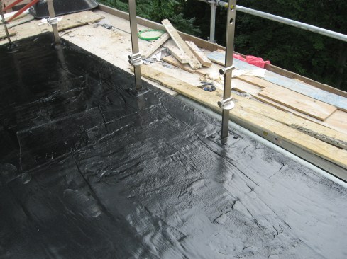 A coat of primer is applied to the metal and the concrete, and finally the reinforced rubberized asphalt is applied over the post base for a robust waterproof seal.