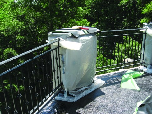 The rubberized asphalt membrane is applied hot, and splashes or drips will stick to anything and are a hassle to clean up. At left, the crew has protected the masonry rail posts with poly.