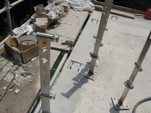 Railing post bases are a common source of leaks in a rooftop patio. The author’s preferred method is to set the bolt in the concrete before waterproofing.