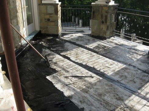 A layer of reinforcing fabric was set over the hot material, then a second layer of coating was applied, embedding the fabric into the rubberized membrane.