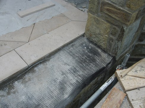 Over the reinforced membrane, the crew layed a dimpled plastic drainage sheet with filter faces, then built up a mortar bed reinforced with galvanized wire mesh.