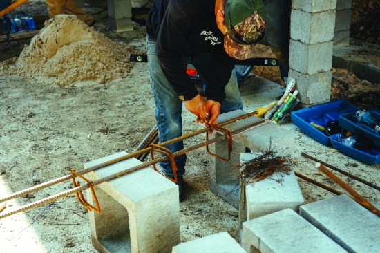 Supporting the heavy slab foundation and its house requires beefy new structure beneath the house. Here, a worker builds a rebar cage for a 16-inch-by-16-inch main support column.