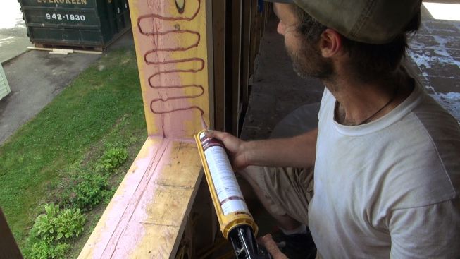 After filling rough parts of the framed opening with Joint and Seam Filler, Kelly starts flashing the entire opening with Prosoco FastFlash.