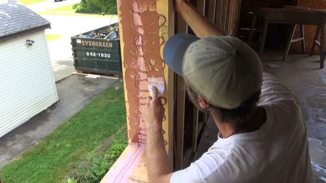 Kelly spreads the FastFlash onto the wood with a plastic trowel.