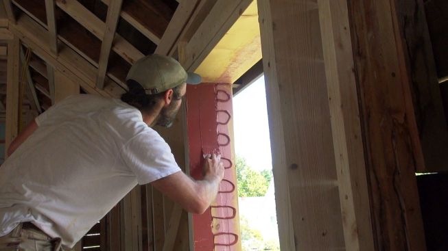 Kelly spreads out the FastFlash with a trowel. The waterproof, vapor-open material creates a smooth surface suitable for later attachment of construction tapes.