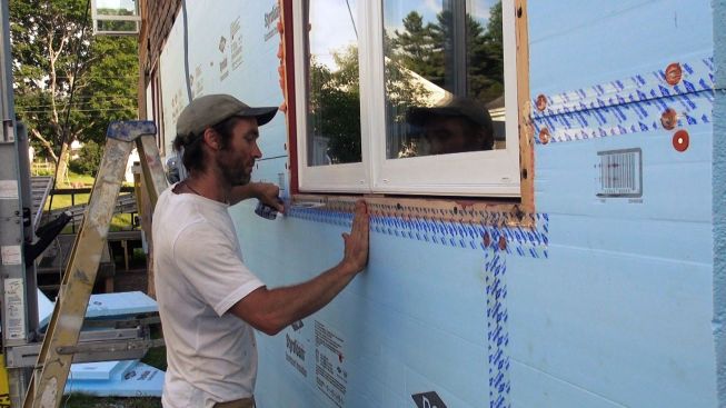 David Kelly seals the juncture between the Dow Styrofoam insulated sheathing and the wood window buck using Dow Weathermate tape. The Dow tape is one of the few tapes available that sticks well to XPS foam, Kelly says, and it's more affordable than many other tapes too.