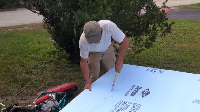 Kelly cuts a piece of Styrofoam with a pull-saw.
