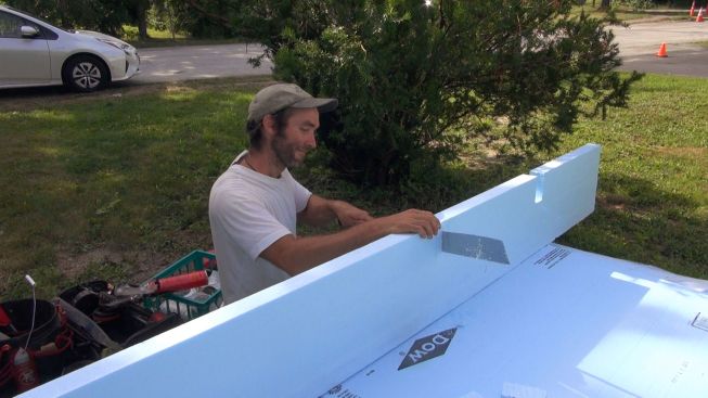 Kelly notches out the foam as he prepares to apply it to the top of the wall.