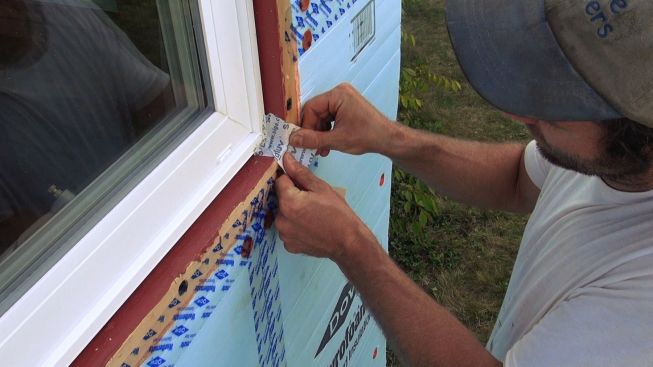 After sealing the Dow Styrofoam to the window buck with Dow Weathermate tape, Kelly ties the window into the drainage plane. Here, he applies a small patch of Siga Wigluv tape at the window buck corner.