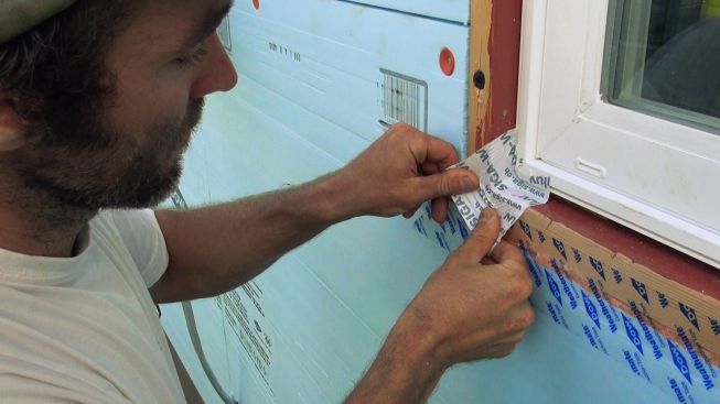 Applying another piece of Sega Wigluv tape at a window buck corner. The product is waterproof and vapor-open. It's also flexible, allowing Kelly to fit the tape to the three-dimensional corner shape.