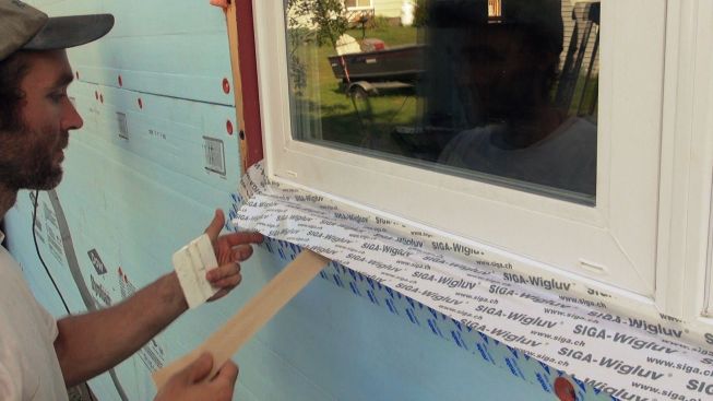 Kelly peels away the Sega Wigluv tape's split-paper backing, which allows him to precisely place the tape first against the window frame, and then against the framed opening.