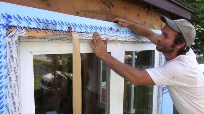 Kelly presses the Sega Wigluv tape over the Dow Weathermate tape at the top of the window. Despite the reverse lap, Kelly is confident that the tape joint is watertight.