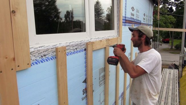 David Kelly screws a piece of strapping underneath the window sill.
