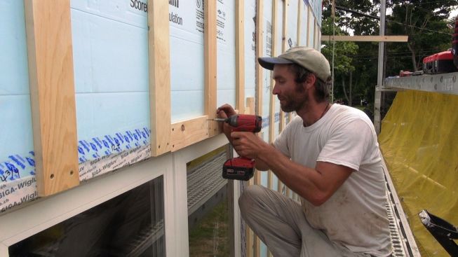 Kelly fills in the 1x4 wood strapping at the head of the window, attaching it with long GRK screws.