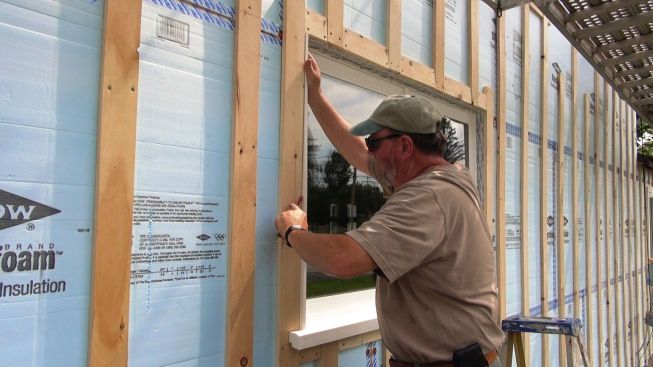 Jay Kelleher scribes a jamb extension. The original house walls were out of plumb, but the windows were placed plumb, so the carpenters have to split the difference as they trim the windows out.