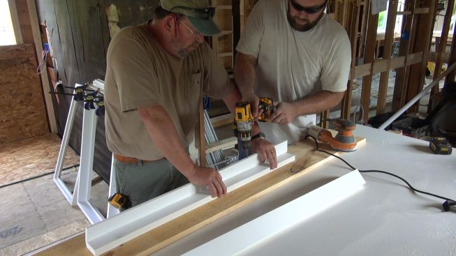 Jay Kelleher and Rick Martin screw Azek jamb extensions to window casing as they trim out the home's windows.