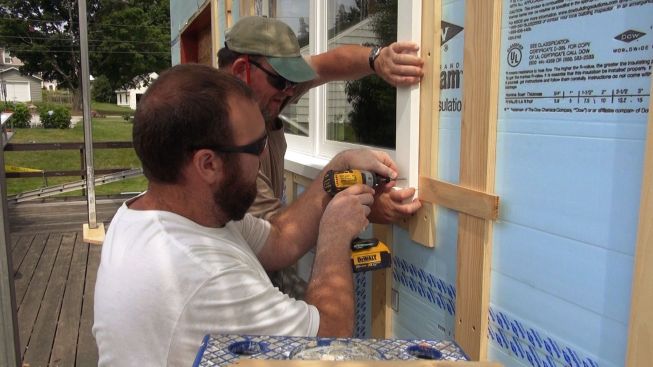 Using shims and screws, Kelleher and Martin fit their window trim pieces to the waterproofed opening and the strapped, insulated wall.