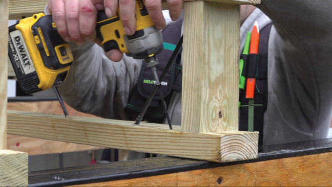 Once a joist is positioned on the 16-inch-on-center layout, it’s fastened to the beam with a pair of structural screws driven down through the bottom chord into the beam.
