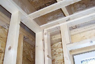Single-stud corners reduce thermal bridging and allow fuller insulation coverage. Wall plates running parallel to the ceiling joists are nailed to 1x3 ceiling strapping, eliminating redundant framing.