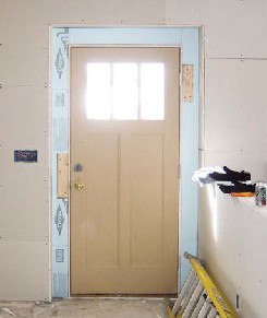 To allow the main entry door to open more fully in the thick exterior wall, the author widened the inside rough opening and applied rigid insulation to the inner face of the exterior wall studs, then sealed all seams with expanding foam.