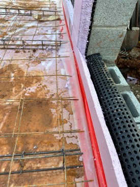 The R-10 rigid XPS extended vertically at slab edges and on the interior of all foundation walls. The seams of the insulation were sealed with vapor impermeable Stego Tape prior to installing a 6-mil vapor retarder and welded wire reinforcing.