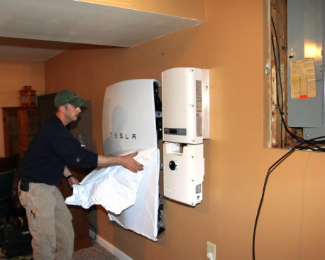 Millette peels the protective shrink-wrap from the face of the Tesla Powerwall battery unit.