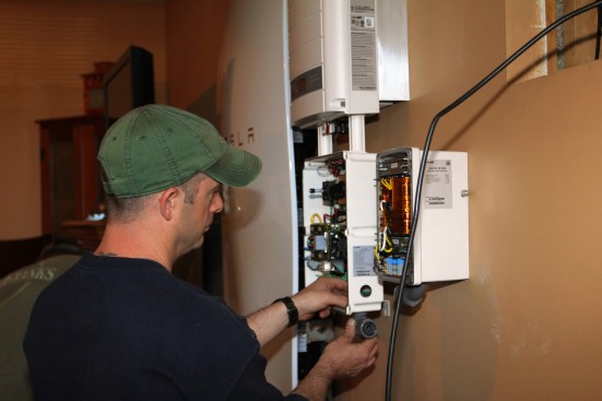 After boring out a hole in the inverter’s enclosure, Millette attaches a conduit fitting to the inverter.