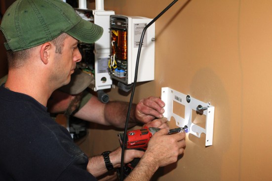 Millette fastens the mounting plate for the smart meter enclosure to the wall.